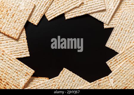 Ein Foto von Matza oder Matza-Stücken auf schwarzem Hintergrund. Matza für die jüdischen Passahfeiertage. Platz für Text, Platz zum Kopieren Stockfoto