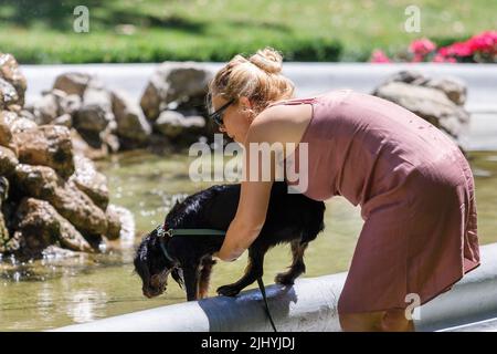 Die Frau kühlt ihren Hund am 21. Juli 2022 in einem Brunnen im Zrinjevac Park in Zagreb, Kroatien, ab. Die zweite Hitzewelle betraf heute einen Teil Kroatiens, und bis Samstag wird sie den Großteil des Landes betreffen. Der Kroatische Wetterdienst und Hydrologischer Dienst gab bekannt, dass die Tagestemperaturen auf dem Höhepunkt der Hitzewelle zwischen 35 und 40 Grad Celsius liegen werden Foto: Tomislav Miletic/PIXSELL Stockfoto