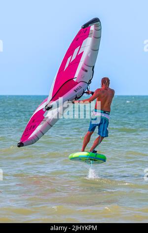 Wing Foiling / Wing Surfing an der Nordsee zeigt Wingboarder / Wing Boarder stehen auf Foilboard / Tragflügelbrett und halten einen aufblasbaren Flügel Stockfoto