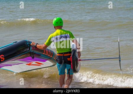 Wing Foiling / Wing Surfing an der Nordsee zeigt Wingboarder / Wing Boarder, die mit Foilboard / Tragflächenboot Board und aufblasbarem Wing ins Wasser kommen Stockfoto