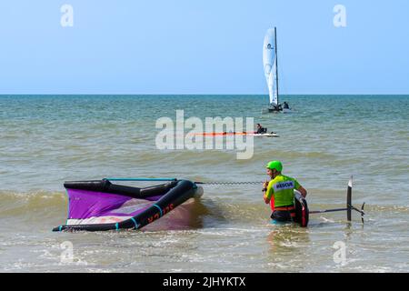 Wing Foiling / Wing Surfing an der Nordsee zeigt Wingboarder / Wing Boarder, die mit Foilboard / Tragflächenboot Board und aufblasbarem Wing ins Wasser kommen Stockfoto