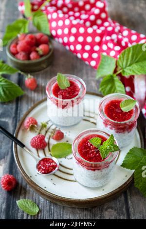 Gesundes Frühstück. Gläser mit Chia-Pudding mit Himbeere und Marmelade oder Smoothies mit Chia-Samen auf rustikalem Tisch. Stockfoto
