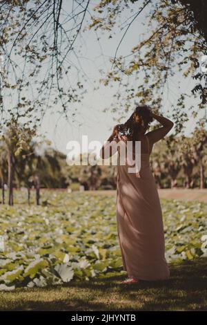 Schöne Frau in rosa Kleid posiert vor dem Garten Stockfoto