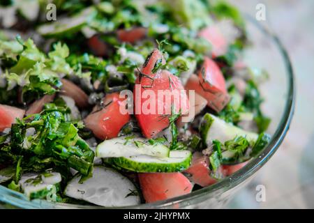 Salat aus frischem Gemüse und Kräutern, mit Pflanzenöl. Nahaufnahme. Stockfoto