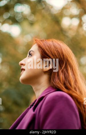 Herbstporträt eines schönen rothaarigen Mädchens mit Herbstblättern im Haar. Stockfoto