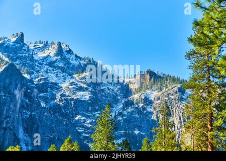 Schneebedeckte Berge im Yosemite-Tal vom Wald aus gesehen Stockfoto