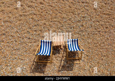 Zwei einlähige Liegestühle an einem Kieselstrand mit viel Platz für Kopien Stockfoto