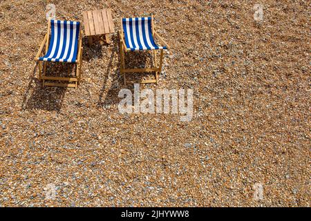 Zwei einlähige Liegestühle an einem Kieselstrand mit viel Platz für Kopien Stockfoto