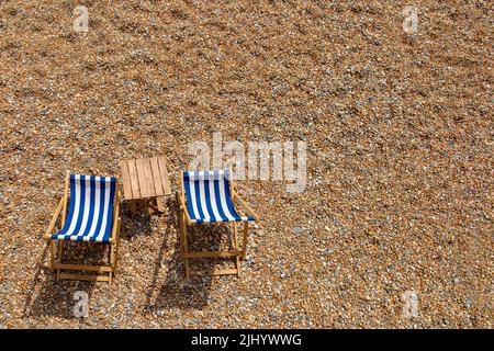 Zwei einlähige Liegestühle an einem Kieselstrand mit viel Platz für Kopien Stockfoto