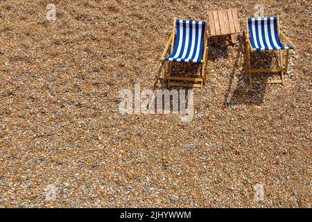 Zwei einlähige Liegestühle an einem Kieselstrand mit viel Platz für Kopien Stockfoto