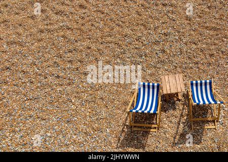 Zwei einlähige Liegestühle an einem Kieselstrand mit viel Platz für Kopien Stockfoto