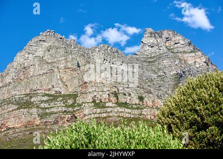 Blick von unten auf majestätische Berge mit Büschen, die unten wachsen und wolkig blauer Himmel kopieren Raum oben. Naturlandschaft von Bergfelsen Aufschlüsse mit wilden Stockfoto