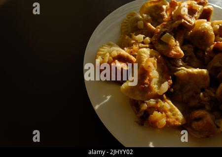 Hausgemachte Kartoffelknödel oder Vereniki pierogi, serviert mit gebratenen Zwiebeln. Rustikaler Stil, komfortable osteuropäische Küche. Stockfoto