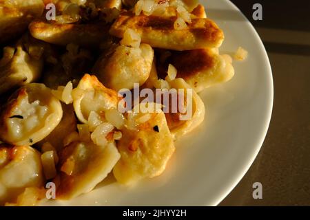 Hausgemachte Kartoffelknödel oder Vereniki pierogi, serviert mit gebratenen Zwiebeln. Rustikaler Stil, komfortable osteuropäische Küche. Stockfoto