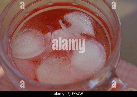 Glas Roselle Saft mit Eis. Traditionelles Getränk. Kräutergetränk. Draufsicht auf Holztisch Stockfoto