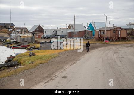 Mann, der auf einer unbefestigten Straße in der Inuvialuit-Gemeinde von Tuktoyaktuk, Nordwest-Territorien, westliche Arktis, Kanada, läuft Stockfoto
