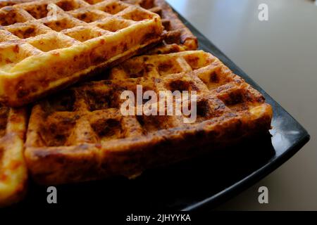 Zum Servieren werden süße Waffeln zubereitet. Ein leckeres Dessert, das mit Obst und Konserven gegessen wird. Dunkler Hintergrund Stockfoto