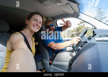 Ein positives Paar, das Selfie im Auto nimmt Stockfoto