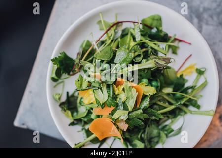 Wildwasser-Salat mit Erbsen und Orangenmimolette Stockfoto