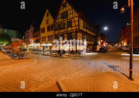 Colmar, Elsass, Frankreich April 2022 : traditionelle Fachwerkhäuser und Restaurants auf der Straße in Colmar in der Dämmerung, Elsass Rigion, Frankreich Stockfoto