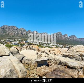 Twelve Apostles at Table Mountain in Kapstadt vor einem klaren blauen Himmel an einem sonnigen Tag mit Kopierfläche. Blick auf einen ruhigen Vorort Stockfoto