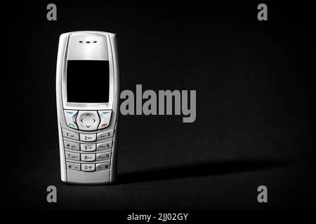Altes silbernes Telefon mit Knöpfen auf schwarzem Hintergrund. Stockfoto