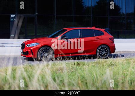 BMW M135i vor dem Gebäude des Internationalen Kongresszentrums.im Vordergrund verschwommenes Gras. Modell F40, Baujahr 2019. 306 PS, 0-100 Stockfoto