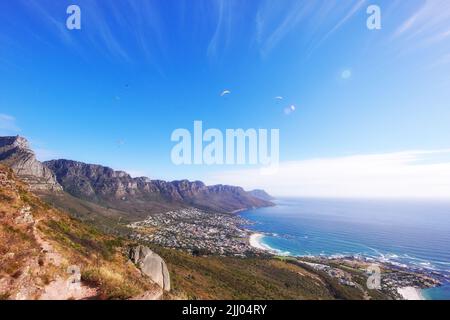 Schöne Panoramasicht auf den Tafelberg in Kapstadt, Südafrika, mit Blick auf das Meer und den Kopierraum. Üppig grüne Büsche und Bäume wachsen weiter Stockfoto