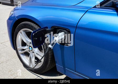 BMW 3er Elektro mit angeschlossenem Kabel während des Ladevorgangs. Eine Nahaufnahme der Fahrzeugfront und der Ladebuchse. Polen, Kattowitz, 01.08.2018 Stockfoto