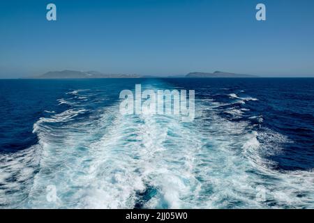 Panoramablick auf die Insel Santorini und Wellenwege eines schwimmenden Fährschiffes Stockfoto