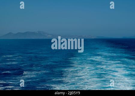 Panoramablick auf die Insel Santorini und Wellenwege eines schwimmenden Fährschiffes Stockfoto