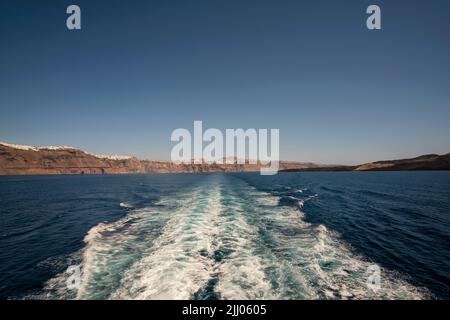 Panoramablick auf die Insel Santorini und Wellenwege eines schwimmenden Fährschiffes Stockfoto