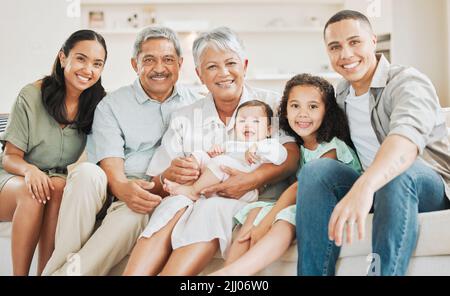 Beten Sie, dass unsere Liebe für immer währt. Eine schöne Familie, die sich zu Hause auf einem Sofa verklebt. Stockfoto