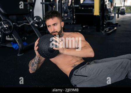 Schöner Mann mit Tattoos in seinem 20s Gewichtheben im Fitnessstudio Stockfoto