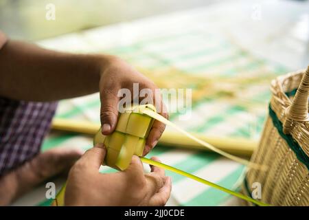 Das Weben der Kokosnussblätter macht den Ketupat, eine traditionelle malaiische Küche während der Eid-Feier. Selektive Fokuspunkte Stockfoto