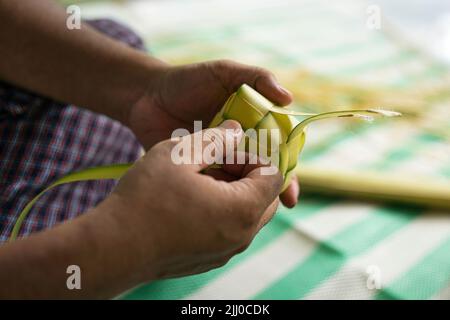 Das Weben der Kokosnussblätter macht den Ketupat, eine traditionelle malaiische Küche während der Eid-Feier. Selektive Fokuspunkte Stockfoto