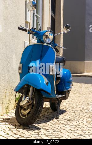 Hellblaues Moped, das auf einer europäischen Straße geparkt ist Stockfoto