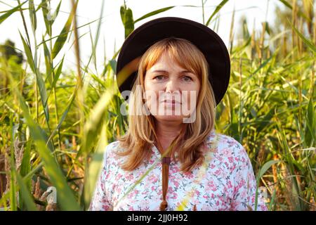 Unschärfe Nahaufnahme außerhalb Porträt der schönen jungen blonden Frau auf Natur Hintergrund. Schatten der Pflanzenkunst. Cowgirl auf der Wiese. Psychische Gesundheit, Stille. L Stockfoto