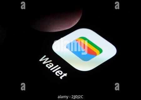 Neue Google Wallet App auf dem Bildschirm des Smartphones und Fingertipp darüber gesehen. Google Pay umbenannt in Google Wallet. Stafford, Großbritannien, Juli Stockfoto