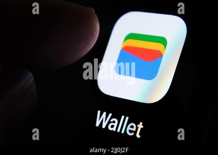 Neue Google Wallet App auf dem Bildschirm des Smartphones und Fingertipp darüber gesehen. Google Pay umbenannt in Google Wallet. Stafford, Großbritannien, Juli Stockfoto