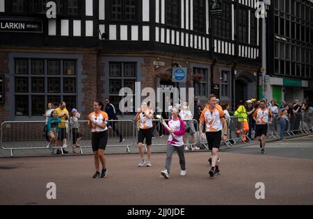 Ein Baton-Träger trägt das Baton der Commonwealth Games Queen durch das Zentrum von Coventry. Stockfoto