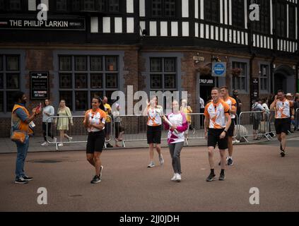Ein Baton-Träger trägt das Baton der Commonwealth Games Queen durch das Zentrum von Coventry. Stockfoto