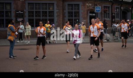 Ein Baton-Träger trägt das Baton der Commonwealth Games Queen durch das Zentrum von Coventry. Stockfoto