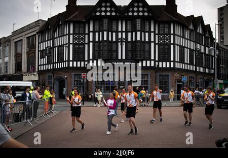 Ein Baton-Träger trägt das Baton der Commonwealth Games Queen durch das Zentrum von Coventry. Stockfoto