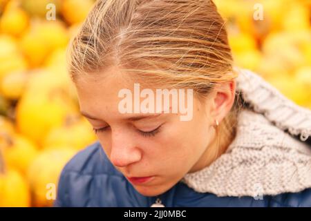 Defocus traurig deprimiert junge Teenager-Mädchen draußen auf gelbem Hintergrund sitzen. Schule, Jugend, häusliche Gewalt, unerwünschte Liebesprobleme. Außerhalb des Fokus Stockfoto