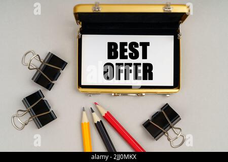 Geschäftskonzept. Auf dem Tisch befinden sich Bleistifte, Büroklammern und ein Visitenkartenhalter, in dem sich eine Visitenkarte mit der Aufschrift befindet - BESTES ANGEBOT Stockfoto
