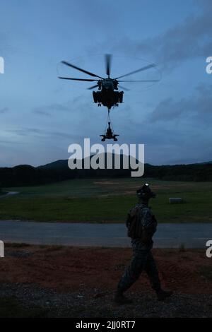 U.S. Marine Corps CPL. Andrew J. Oldroyd, ein Landeunterstützungsspezialist, mit Combat Logistics Bataillon 31, 31. Marine Expeditionary Unit, beobachtet einen CH-53E Superhengst mit Marine Medium Tiltrotor Squadron 262 (verstärkt), 31. MEU, hebt eine M777 geschleppte 155 mm Haubitze während des Hubschrauberunterstützungsteams-Trainings in Camp Hansen, Okinawa, Japan, vom Boden 19. Juli 2022. Die HST ermöglicht die Einrichtung einer zweckdienlichen Landezone für Flugzeuge und ist in der Lage, Ausrüstung wie Joint Light Tactical Vehicles und Haubitzen für die Abholung zu sichern. Die 31. MEU, das einzige fortlaufende Forward-Corps des Marine Corps, Stockfoto