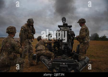 Fallschirmjäger der US-Armee, die einer Batterie zugewiesen wurden, 4. Bataillon, 319. Field Artillery Regiment, 173. Airborne Brigade, Feuermunition einer M119A3 Haubitze während einer Trainingsübung auf dem Trainingsgelände in Grafenwoehr, Deutschland, 7. Juli 2022. (USA Armeefoto von Sgt. Randis Monroe) Stockfoto