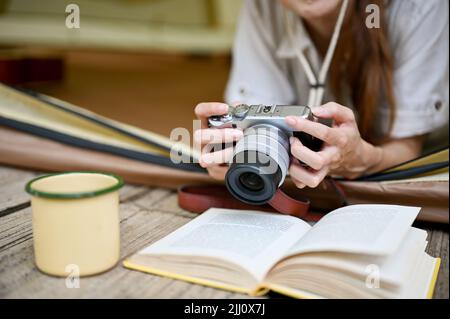 Junge asiatische Frau, die in ihrem Campingzelt lag und mit der Kamera ihr schönes Waldbild überprüfe. Camping-Konzept. Zugeschnittenes und Nahaufnahme Bild Stockfoto