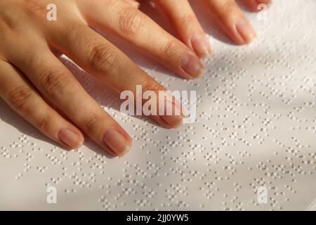 Die Finger einer Frau auf einer Buchseite mit Braille Stockfoto